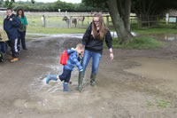 Teacher and pupil playing in muddy water puddle