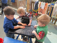 Three nursery pupils playing together around a table